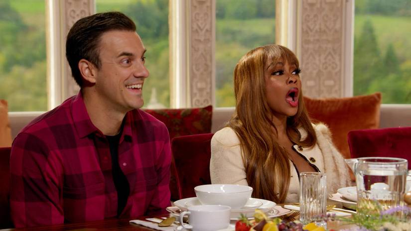 Dan Gheesling and Phaedra Parks seated at a breakfast table, reacting to conversation on The Traitors
