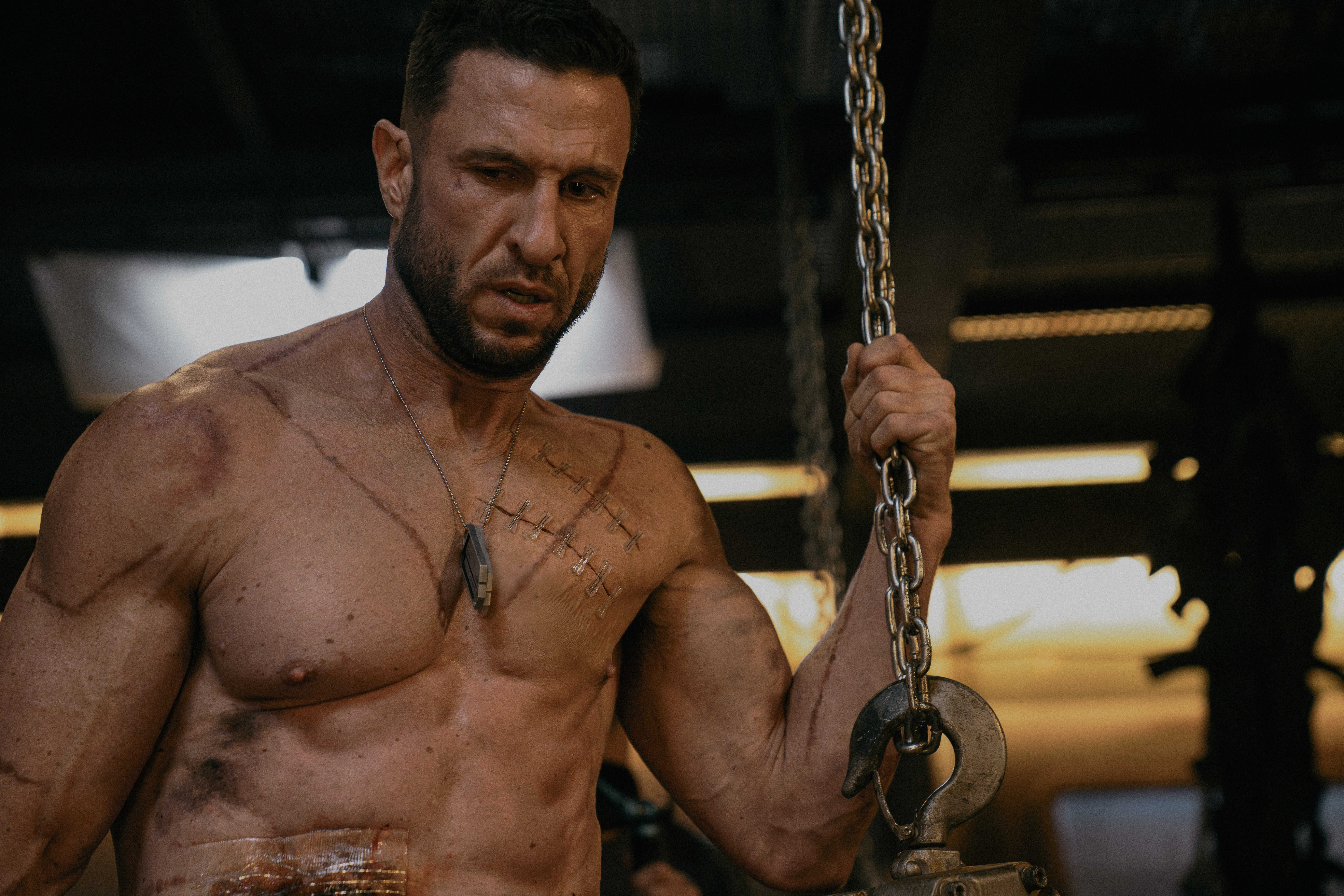 Pablo Schreiber as Master Chief in Halo season 2 standing shirtless holding onto a chain for some reason