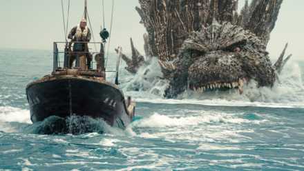 A mostly submerged Godzilla snarls and zooms toward a ship on the sea in Godzilla Minus One