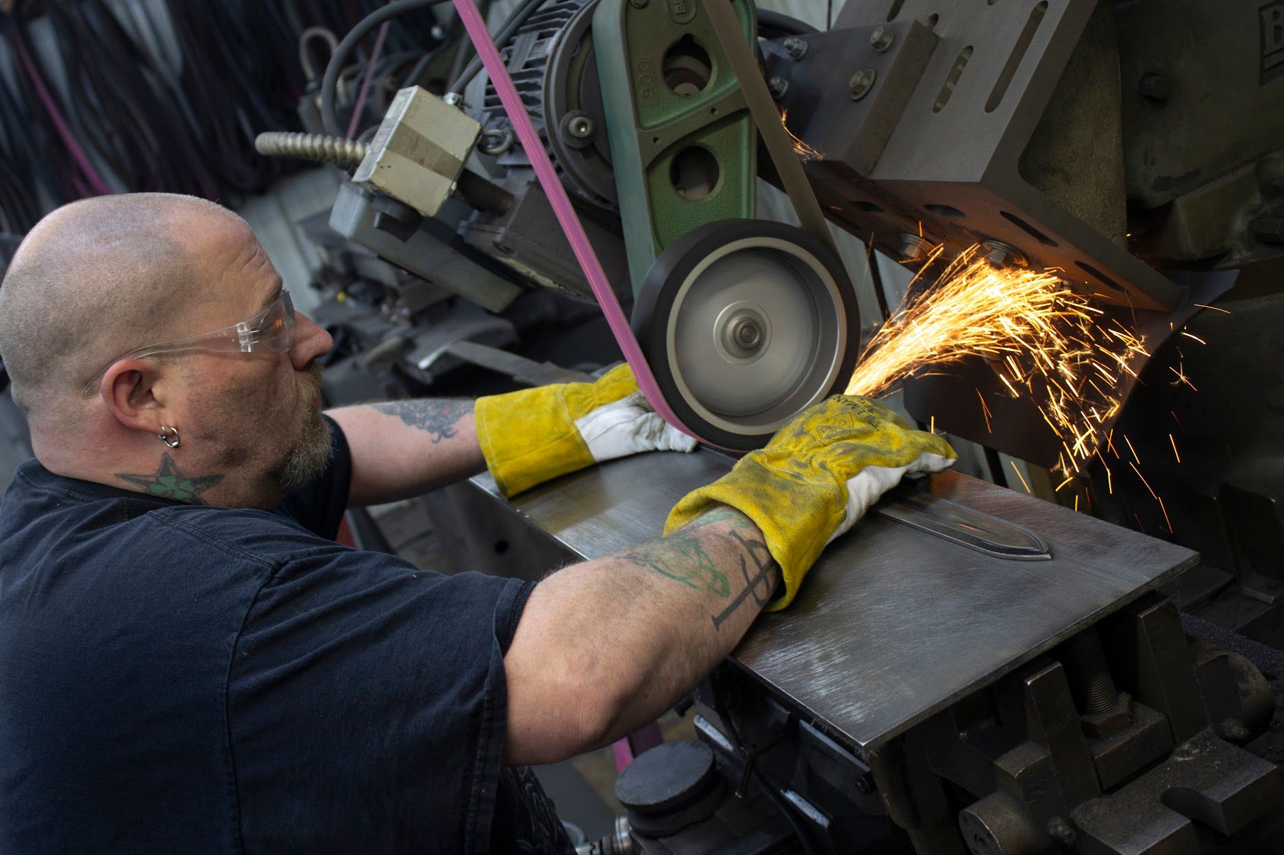 A worker at Sabersmith sharpens a claymore.