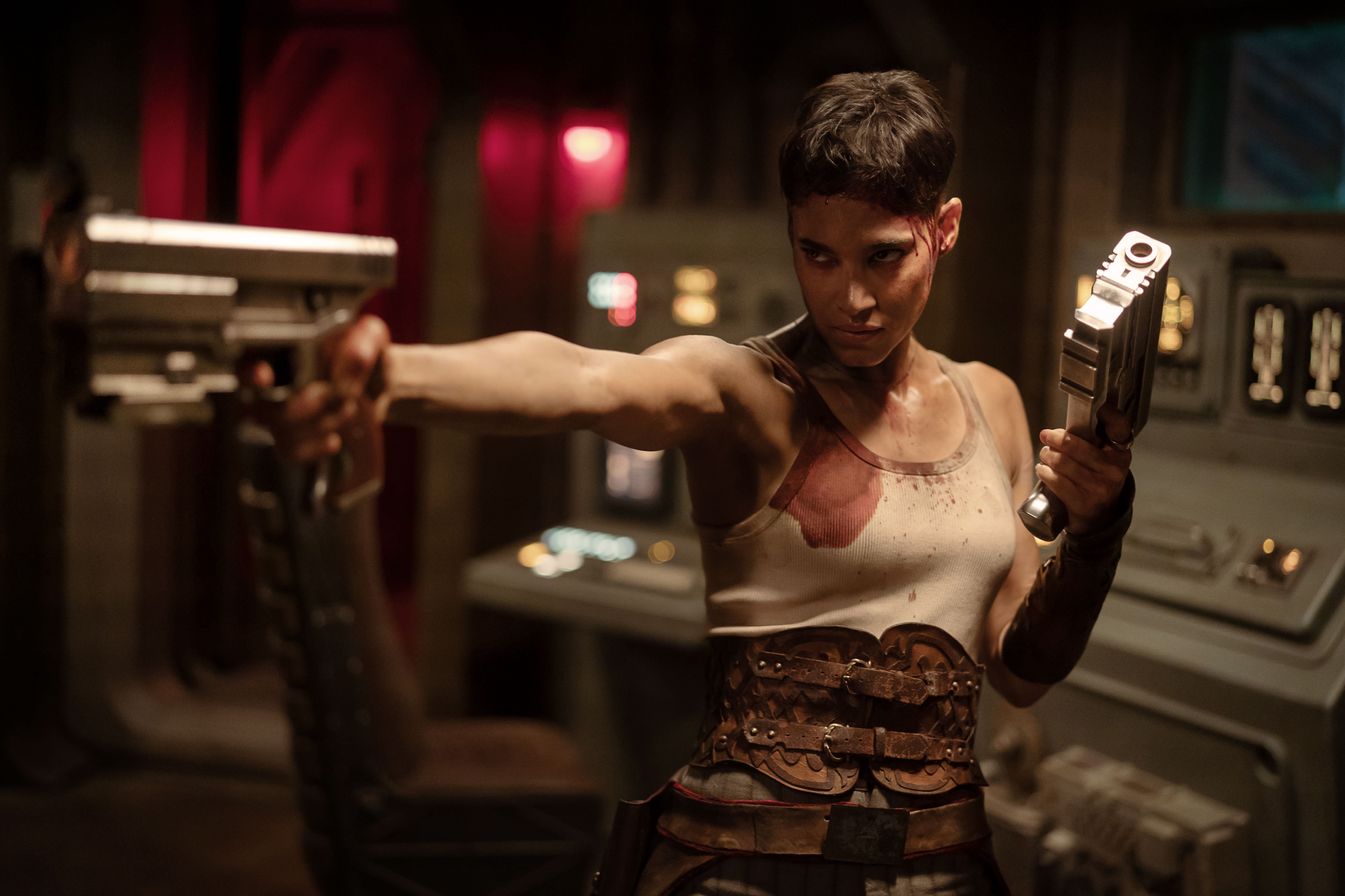 Sofia Boutella as Kora holding up guns