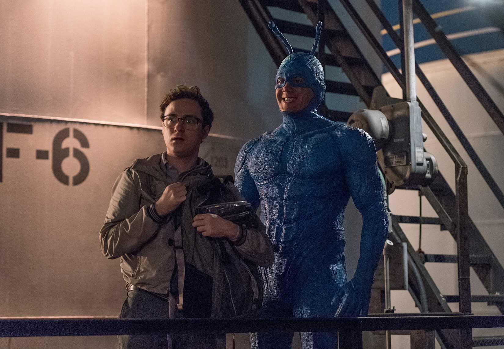 The Tick grins widely as Arthur looks confused