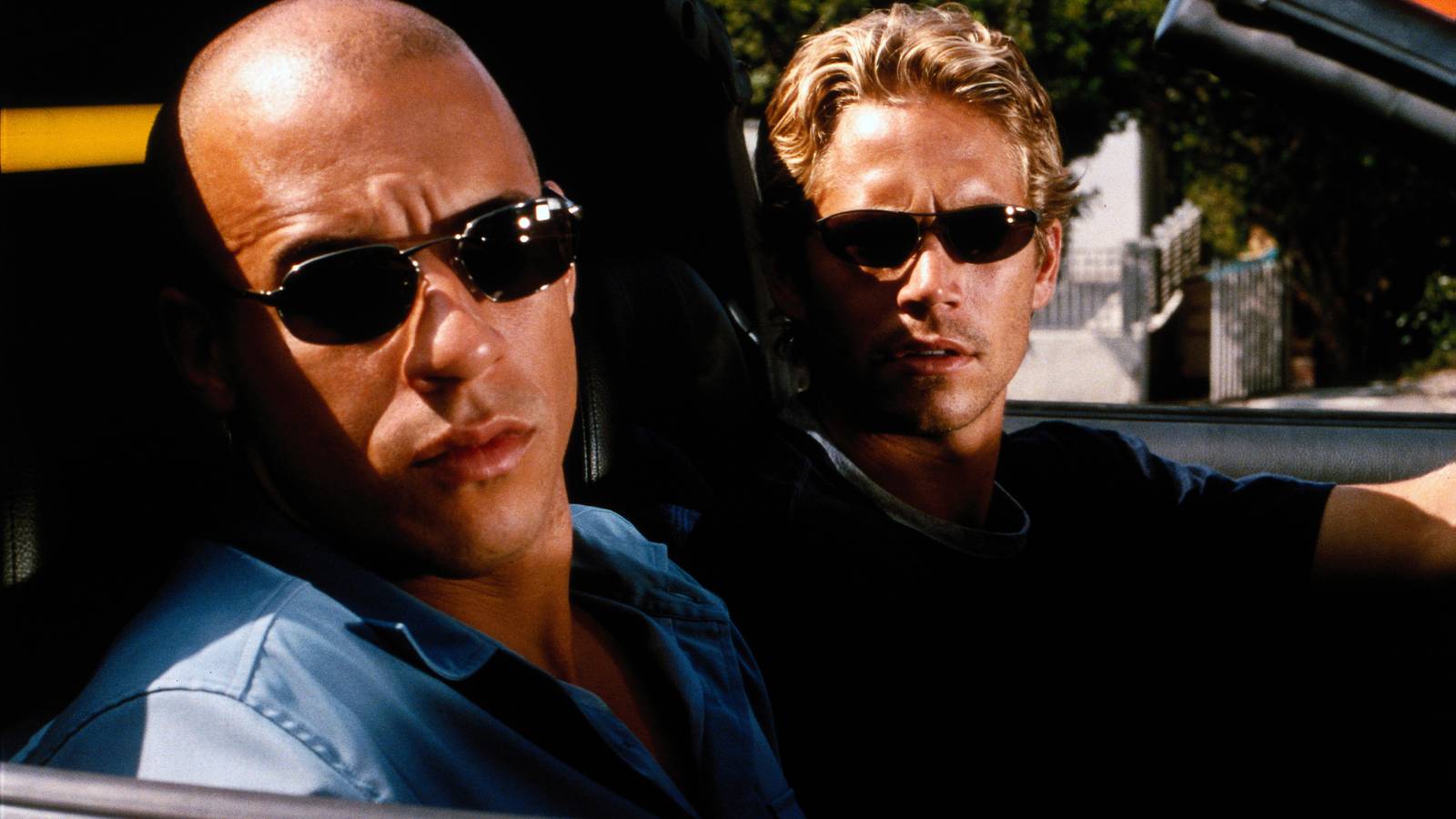 Vin Diesel and Paul Walker wear sunglasses with furrowed brows in a convertible in The Fast and The Furious